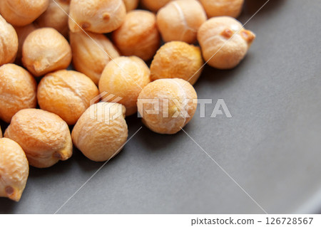 Dry chickpea beans on black ceramic plate surface. Macro. Uncooked protein fiber diet ingredient.  126728567