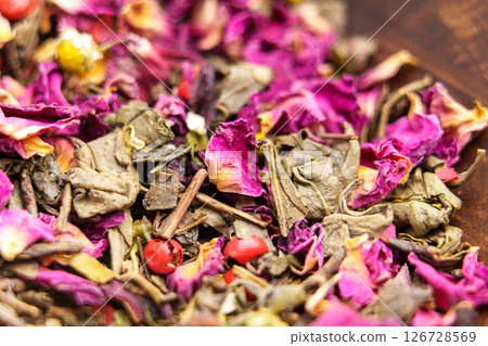 Green herbal flower tea with chamomile, hibiscus and red peppercorns. Macro shot Green herbal flower tea with chamomile, hibiscus and red peppercorns. Macro shot 126728569