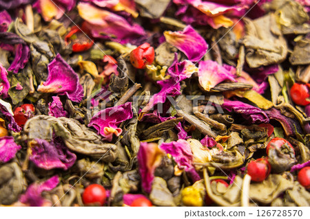 Falling leaves and petals of green herbal flower tea with chamomile, hibiscus, red peppercorns. Macro shot. Falling leaves and petals of green herbal flower tea with chamomile, hibiscus, red peppercorns. Macro shot. 126728570