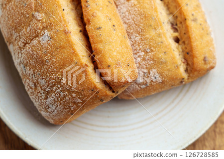 Freshly toasted fluffy wheat buns on a kitchen plate. Cracked bread. Top view.  126728585