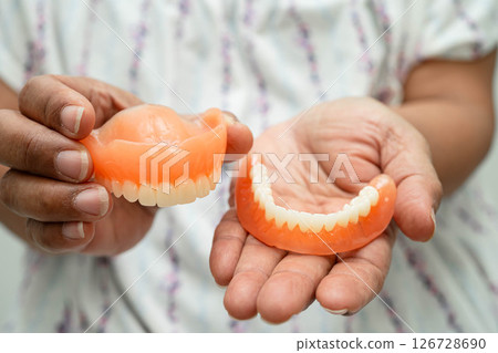 Asian senior woman holding denture teeth. Asian senior woman holding denture teeth. 126728690