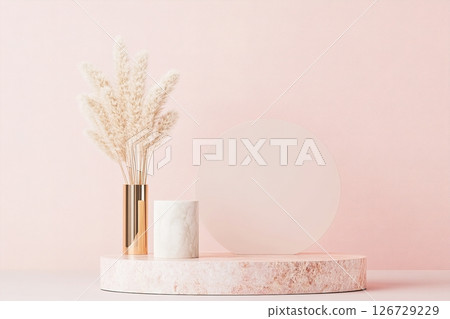 A refined display features soft acrylic elements in blush pink and rose gold, complemented by decorative pampas grass in a sleek vase, enhancing an elegant atmosphere 126729229