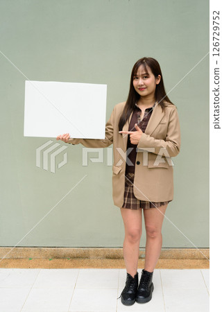 Asian young woman holding a blank board copyspace Asian young woman holding a blank board copyspace 126729752