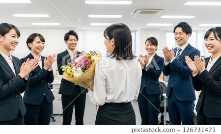 辦公室裡,一位女士手捧鮮花,周圍都是掌聲雷動的人群 辦公室裡,一位女士手捧鮮花,周圍都是掌聲雷動的人群 126731471