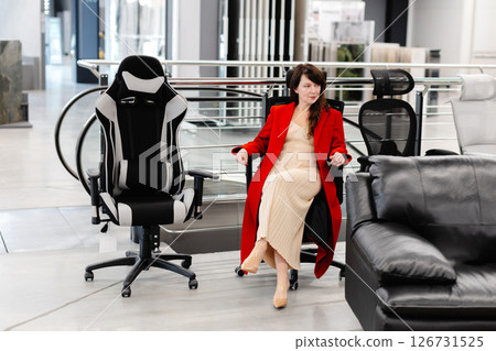 Elegant woman trying new office chairs in furniture store 126731525
