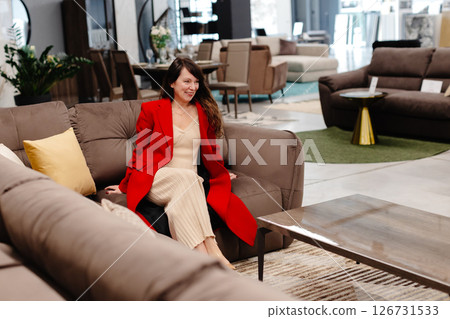 Woman relaxing on comfortable sofa in furniture store showroom Woman relaxing on comfortable sofa in furniture store showroom 126731533