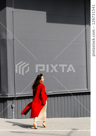 Businesswoman walking in the city wearing elegant red coat Businesswoman walking in the city wearing elegant red coat 126731541