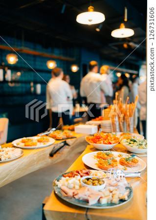 Delicious spread of appetizers at a bustling gathering in a modern venue during an evening event 126731606