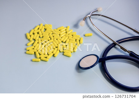 A bunch of yellow pills and stethoscope on a blue A bunch of yellow pills and stethoscope on a blue 126731704
