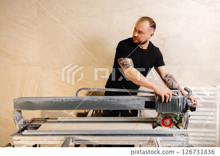 Construction worker using tile saw cutting machine preparing ceramic tiles for bathroom renovation Construction worker using tile saw cutting machine preparing ceramic tiles for bathroom renovation 126731836