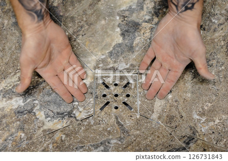 Construction worker placing travertine tiles in shower floor during bathroom renovation 126731843
