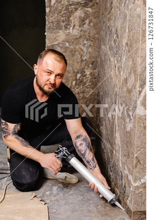 Construction worker applying silicone sealant on tiles in bathroom 126731847