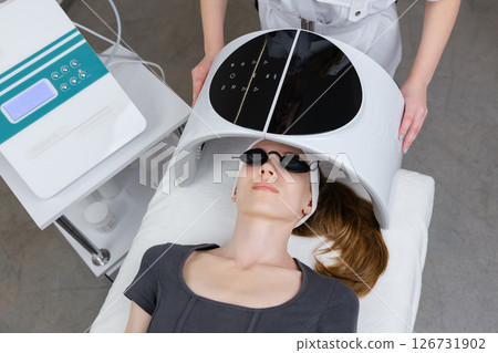 Beautician using led light therapy facial device on client for skin rejuvenation 126731902