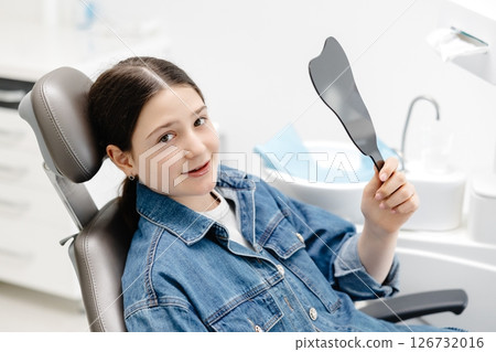 Young patient admiring her smile after dental checkup 126732016