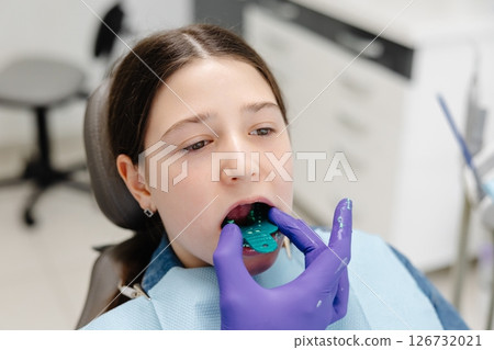 Dentist placing impression tray in girl's mouth for dental care Dentist placing impression tray in girl's mouth for dental care 126732021