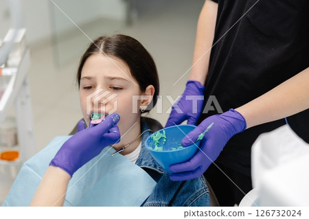 Dentist applying dental sealant on teeth of teenage girl Dentist applying dental sealant on teeth of teenage girl 126732024