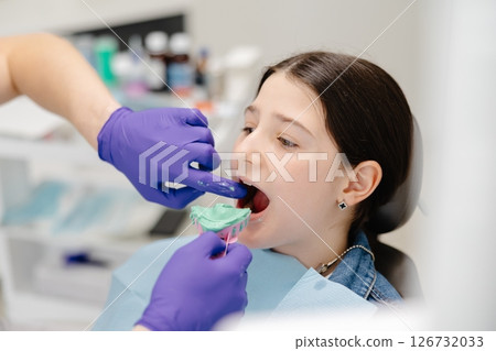 Dentist placing impression tray in girl's mouth for dental care 126732033