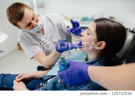 Dentist applying dental sealant on teeth of teenage girl 126732036