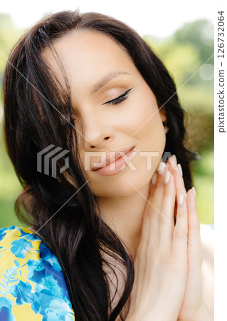 Portrait of a beautiful young woman standing at the green leaves tree Portrait of a beautiful young woman standing at the green leaves tree 126732064