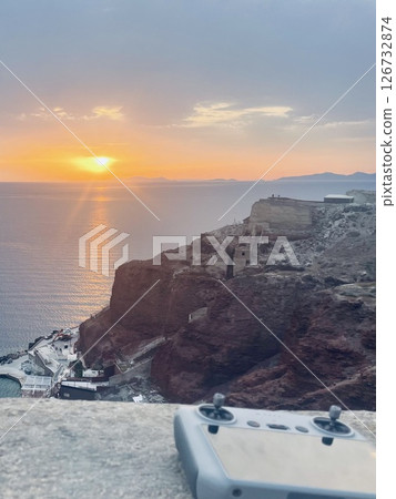 Drone remote control against the sunset in the town of Oia on the volcanic island of Santorini 126732874