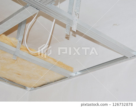 Installing ceiling metal frame with U-shaped brackets and mineral wool insulation for drywall - home renovation step 126732878