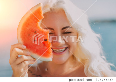 Watermelon Woman Summer Beach: Happy woman enjoys juicy watermelon slice near ocean, sunny day. Watermelon Woman Summer Beach: Happy woman enjoys juicy watermelon slice near ocean, sunny day. 126733232