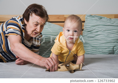 Grandmother Playing with Baby and Wooden Toy Airplane 126733902
