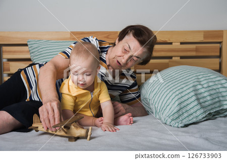 Grandmother Playing with Baby and Wooden Toy Airplane 126733903