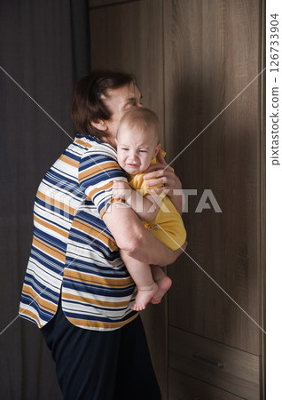 Grandmother Comforting Crying Baby at Home 126733904