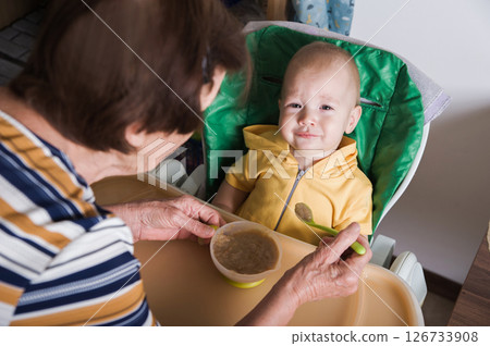 Happy Baby Being Fed by Grandmother at Home Happy Baby Being Fed by Grandmother at Home 126733908