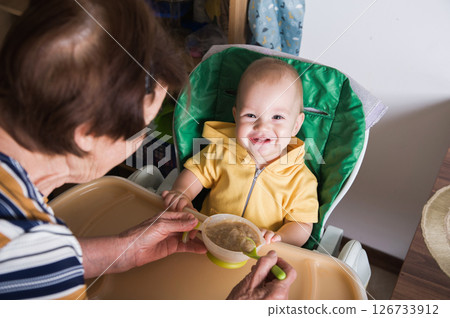 Happy Baby Being Fed by Grandmother at Home Happy Baby Being Fed by Grandmother at Home 126733912
