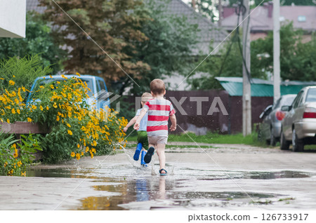 Two Young Children Running Through Rain Puddles in Summer Neighborhood Two Young Children Running Through Rain Puddles in Summer Neighborhood 126733917