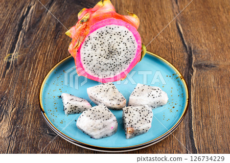 Close-up of half of pitahaya fruit and pieces of fruit pulp. 126734229