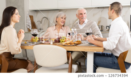 Senior parents and young couple sitting at table drinking wine and having conversation 126734394