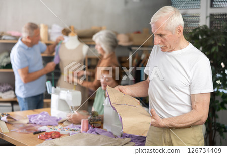 Elderly man reviewing paper pattern in training sewing workshop 126734409