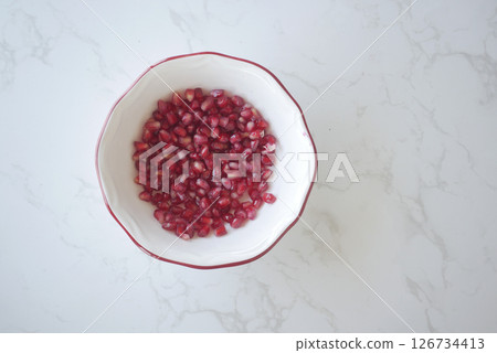 Fresh pomegranate seeds in a bowl on a marble surface Fresh pomegranate seeds in a bowl on a marble surface 126734413