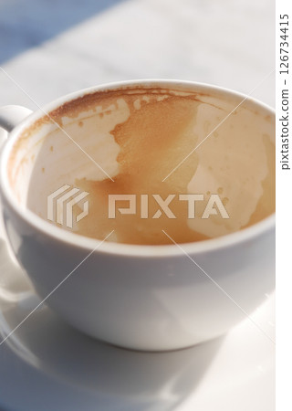 Coffee cup with remnants of beverage on a sunny morning Coffee cup with remnants of beverage on a sunny morning 126734415