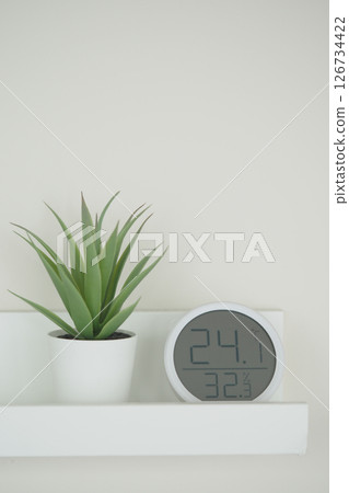 Indoor plant and digital clock on a minimalist shelf 126734422
