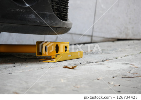 Vehicle immobilizer placed under a parked car in a garage 126734423