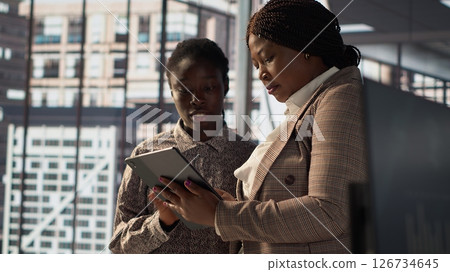 Business associates reviewing objectives data and performance metrics in a modern office, focusing on corporate strategy and decision making for sustainable enterprise development. Camera A. 126734645