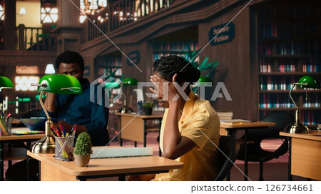 Tired frustrated university student struggling to memorize information on the papers, trying to learn class notes for an upcoming exam. Stressed pupil with lack of motivation. Camera A. Tired frustrated university student struggling to memorize information on the papers, trying to learn class notes for an upcoming exam. Stressed pupil with lack of motivation. Camera A. 126734661