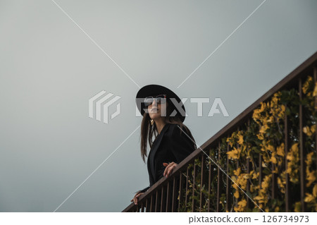 Elegant Coat Women Posing On The Railing In The Medieval Italian Town Square Elegant Coat Women Posing On The Railing In The Medieval Italian Town Square 126734973