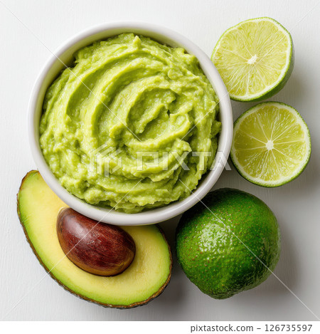 Creamy guacamole in bowl with fresh lime and avocado on white background 126735597