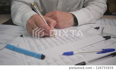 Close Examination of Financial Documents With a Person Writing Notes in an Office, Illustrating Meticulous Attention to Detail During Data Analysis Close Examination of Financial Documents With a Person Writing Notes in an Office, Illustrating Meticulous Attention to Detail During Data Analysis 126735859