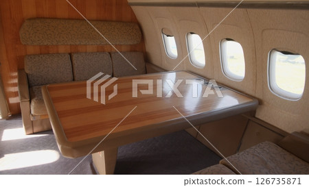 Luxurious Aircraft Interior Featuring a Spacious Seating Area and Elegant Wooden Table, Perfect for Relaxation or Meetings on Long Flights Luxurious Aircraft Interior Featuring a Spacious Seating Area and Elegant Wooden Table, Perfect for Relaxation or Meetings on Long Flights 126735871