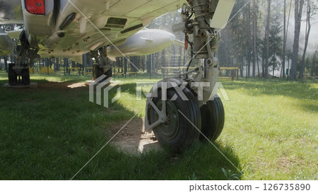 Landing Gear of a Vintage Aircraft on a Grassy Field Surrounded by Trees in a Serene Location During Daylight Landing Gear of a Vintage Aircraft on a Grassy Field Surrounded by Trees in a Serene Location During Daylight 126735890