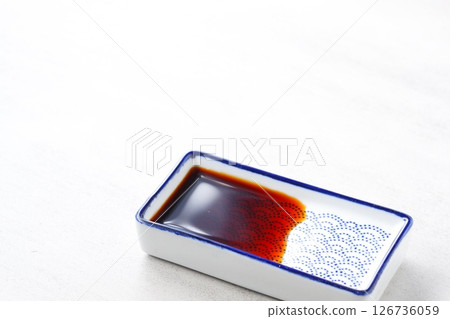 A small Japanese-style dish filled with soy sauce A small Japanese-style dish filled with soy sauce 126736059