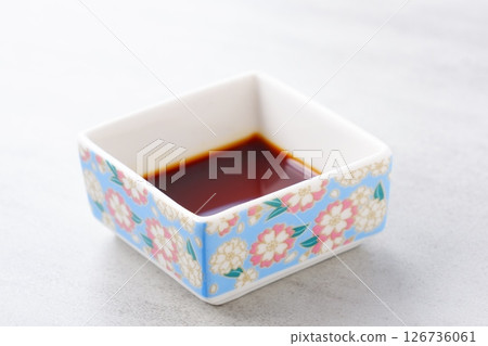 A small Japanese-style dish filled with soy sauce A small Japanese-style dish filled with soy sauce 126736061