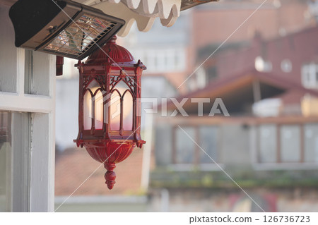 Elegant red lantern hangs near cozy urban balcony 126736723