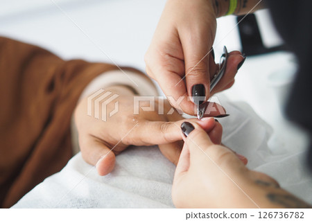 Nail technician performing manicure on a client's hand 126736782